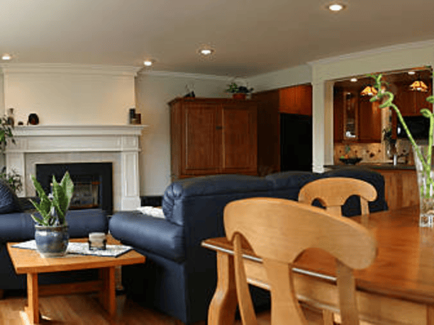 room with blue couch, dining table with chairs and kitchen off to the right